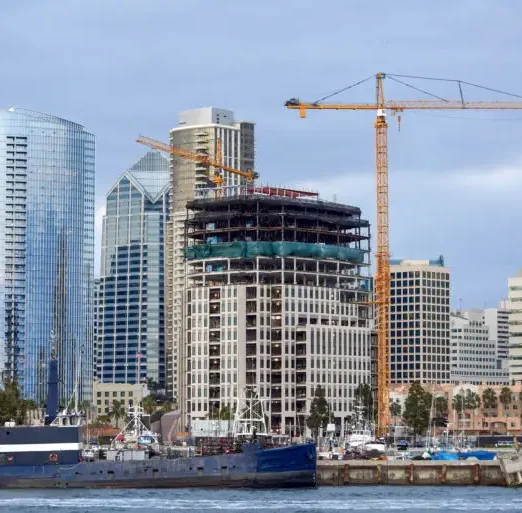 Construction works and high, modern buildings, yachts and two old moored boats on the foreground in San Diego, USA