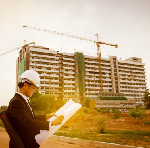 Young asian engineer looking paper plan of the building