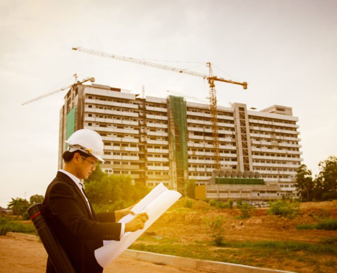 Young asian engineer looking paper plan of the building